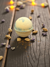 Load image into Gallery viewer, Bath bomb on a wooden surface with dried lavender flowers