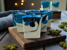 Load image into Gallery viewer, Blue and white swirl handmade soaps on a wooden board with soft lights in the background