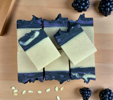 Load image into Gallery viewer, Three bars of soap with a blue and white marbled design on a wooden surface with blackberries and seeds.