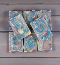Load image into Gallery viewer, Colorful swirled soap bars on a wooden surface