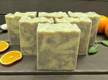 Load image into Gallery viewer, Handmade Orange and Patchouli Soap bars with a natural marbled pattern, displayed on a wooden surface with fresh orange slices and leaves