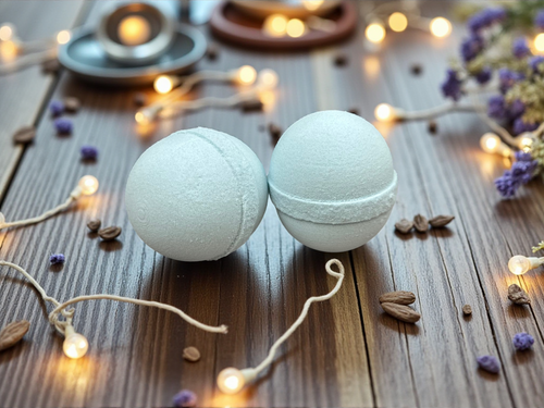 Two bath bombs on a wooden surface with decorative lights and herbs.