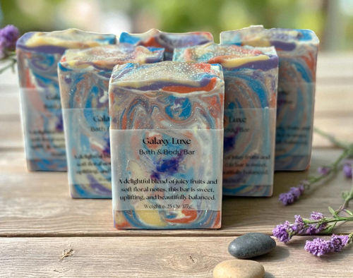 Galaxy Luxe bath and body bars on a wooden surface with lavender flowers.