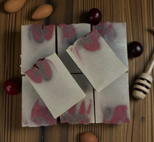 Load image into Gallery viewer, Three rectangular soap bars with marbled pink and gray design on a wooden surface with cherries and almonds.
