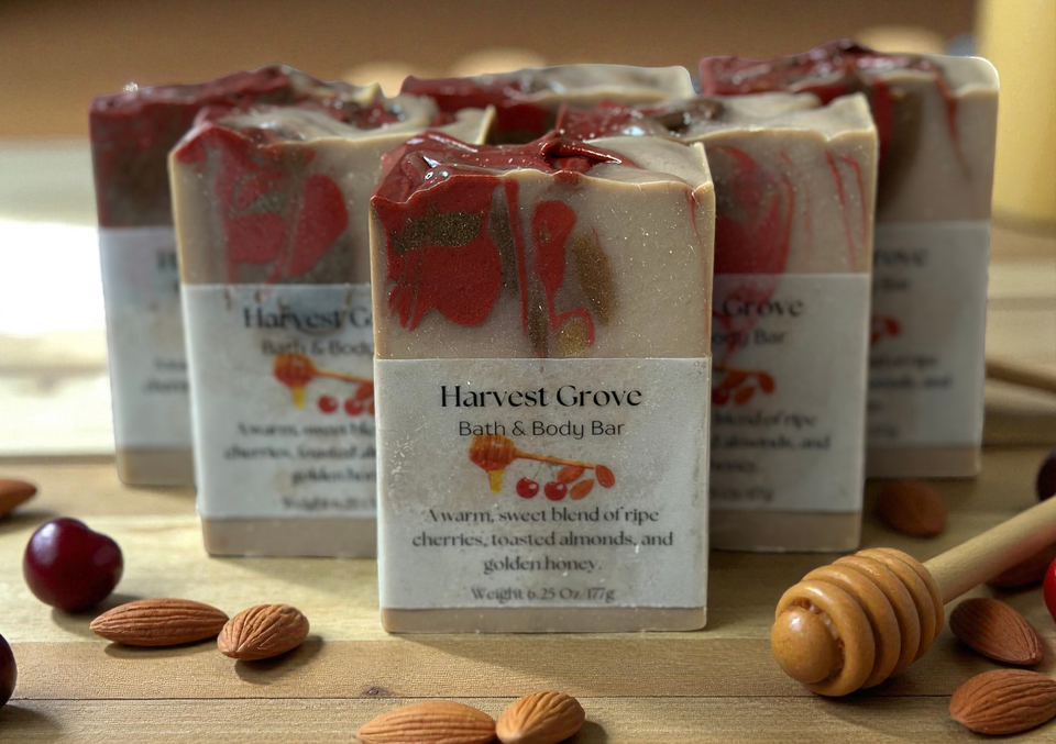 Harvest Grove bath and body bars on a wooden surface with cherries, almonds, and honey.