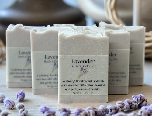 Lavender bath and body bars on a wooden surface with lavender flowers.