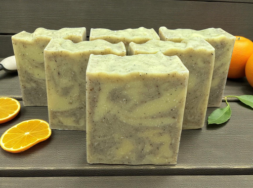 Handmade Orange and Patchouli Soap bars with a natural marbled pattern, displayed on a wooden surface with fresh orange slices and leaves
